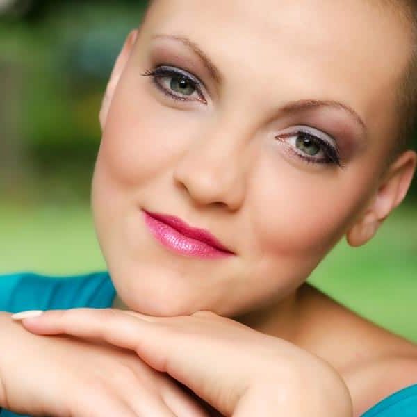 almost bald woman after chemotherapy with pink lipstick