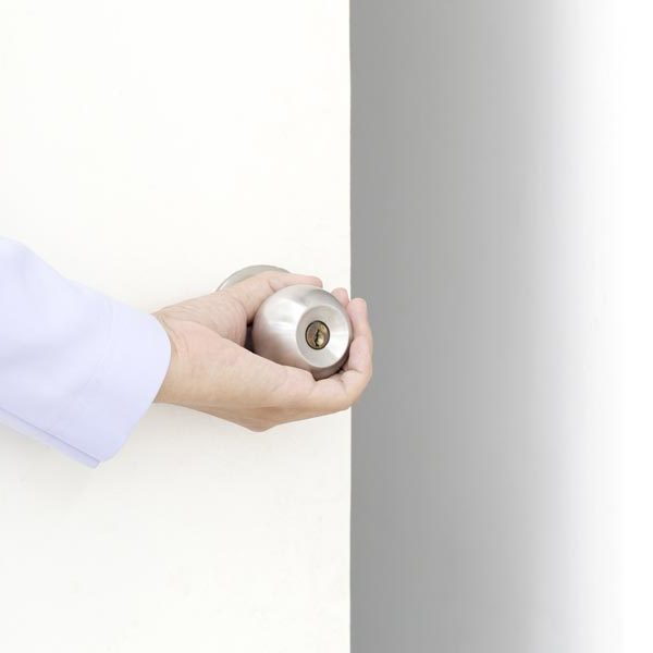 hand opening a white door with silver door knob
