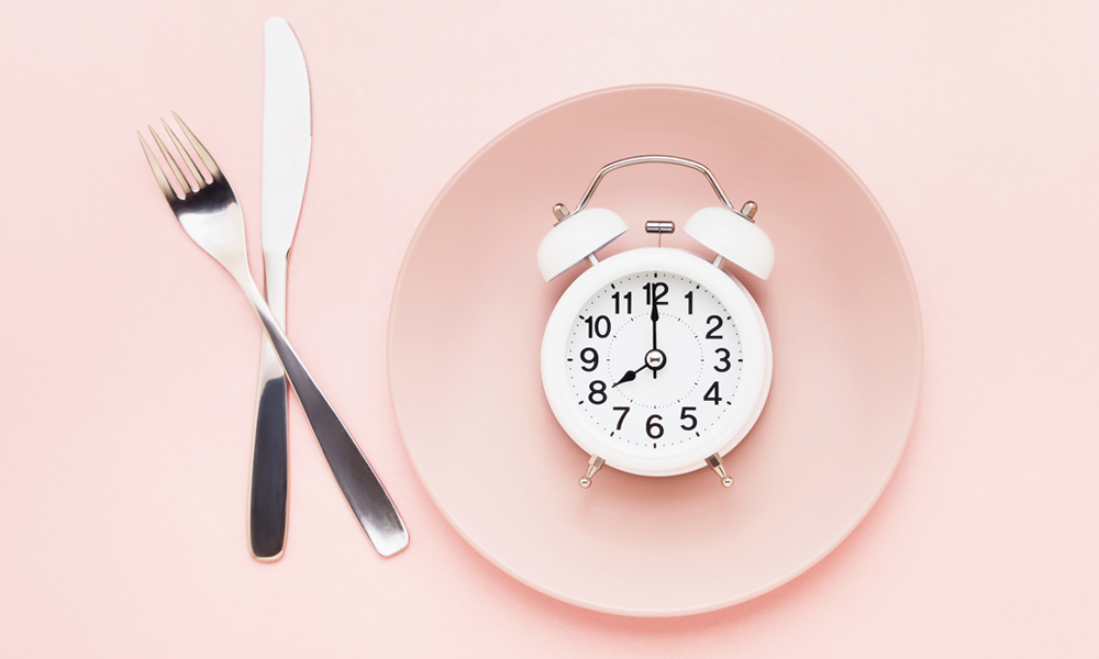 fasting theme with plate and alarm clock on pink background